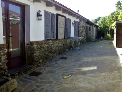 corredor empedrado del albergue, con la fachada encalada y las puertas de los dormitorios