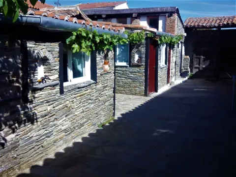 pasillo exterior de piedra del albergue, cubierto por la parra