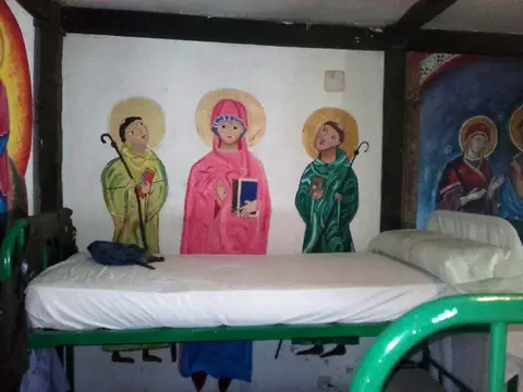 cama del albergue junto al mural de santos peregrinos pintado en la pared