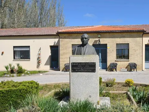 fachada principal de la casa, con el jardín delantero y el busto del fundador