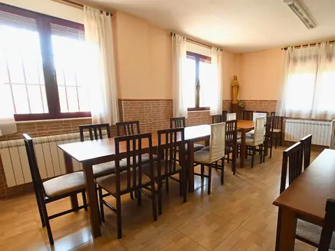 comedor de la casa, con mesas de madera y ventanales al jardín