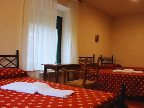 habitación triple de la casa, con tres camas y mesa junto a la ventana