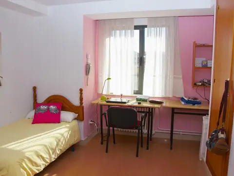 habitación individual del colegio, con cama, mesa de estudio y baño propio
