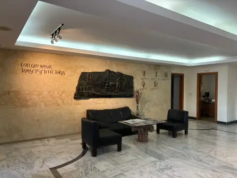 hall de recepción del colegio, con los sofás y el relieve de la pared