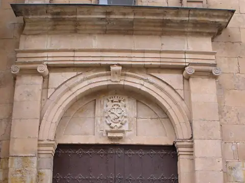 portada gótico-renacentista del convento, con el escudo sobre el arco y la puerta de madera