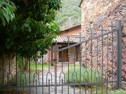 entrada de la hospedería: la verja de hierro y el patio empedrado con el porche de acceso