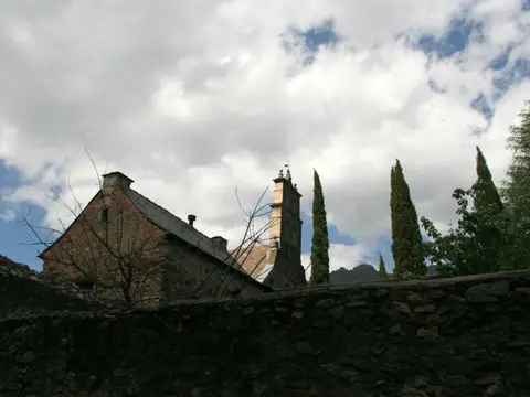 los edificios del monasterio tras la tapia de piedra, con los cipreses del recinto
