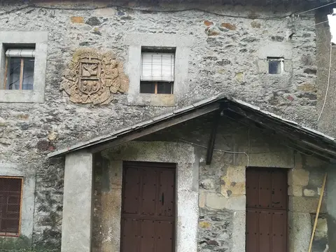 fachada de piedra del monasterio con el escudo y las puertas de madera, desde el patio de entrada