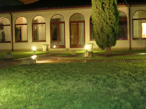 galería acristalada del colegio de noche, con el césped y los cipreses