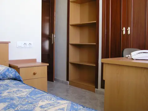 habitación de la residencia, con cama, armario, estantería y escritorio