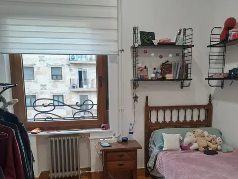 otra de las habitaciones, con cama, mesilla y radiador bajo la ventana
