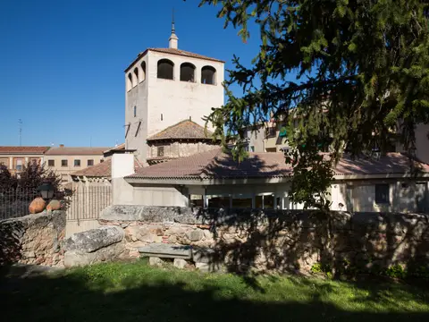 el edificio y su jardín, con la torre de la iglesia de San Clemente al fondo