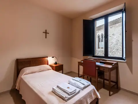 celda de la hospedería interna con cama y escritorio