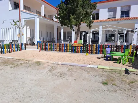 exterior del edificio, con el porche y la zona de juegos vallada