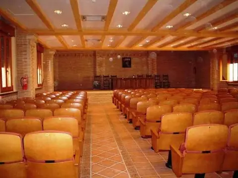 aula magna de la Casa de Espiritualidad, con butacas y techo de vigas de madera