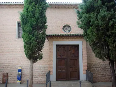 fachada de ladrillo de la iglesia del monasterio, con la portada y los cipreses