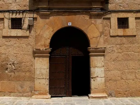 portada de piedra del convento, con el escudo trinitario sobre el arco