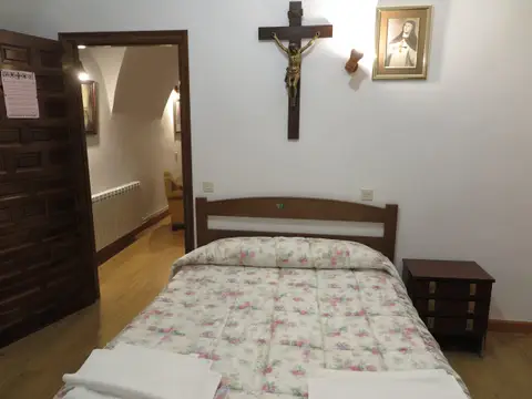 habitación de la hospedería con cama de matrimonio y crucifijo