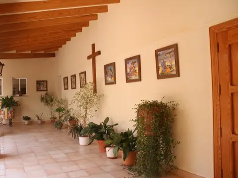galería interior con vigas de madera y vía crucis en las paredes
