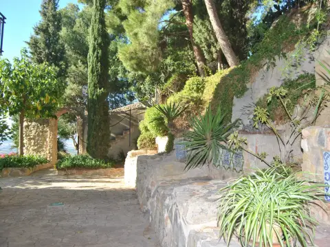 jardín y camino empedrado del recinto, con los azulejos y el arco de piedra
