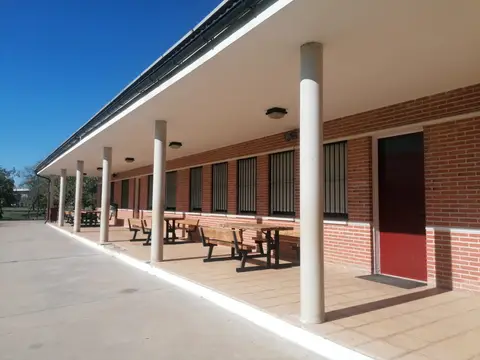 soportales exteriores del albergue, con mesas y bancos